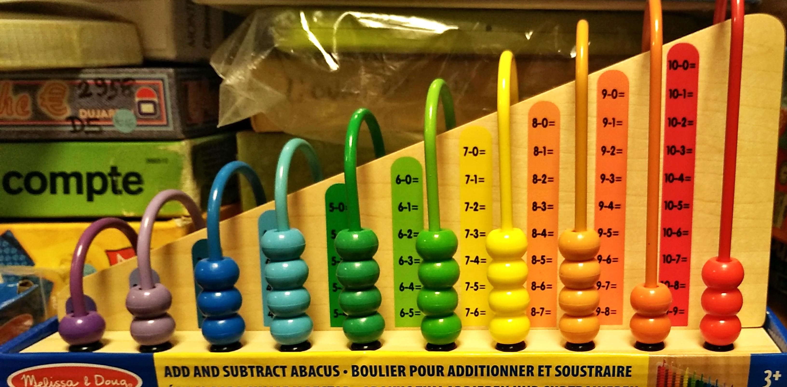 BOULIER APPRENTISSAGE<br>Référence ludothèque : 4104<br>1 à 2 joueur(s) <br>Ce boulier propose plusieurs façons d’explorer les chiffres, les couleurs et les motifs. Il suffit de faire glisser les deux planches en bois à double face dans la base, puis d’encourager les enfants à résoudre les équations en alignant le bon nombre de boules sur les faces addition et soustraction ou à suivre les motifs sur les faces d’appariement de couleurs
